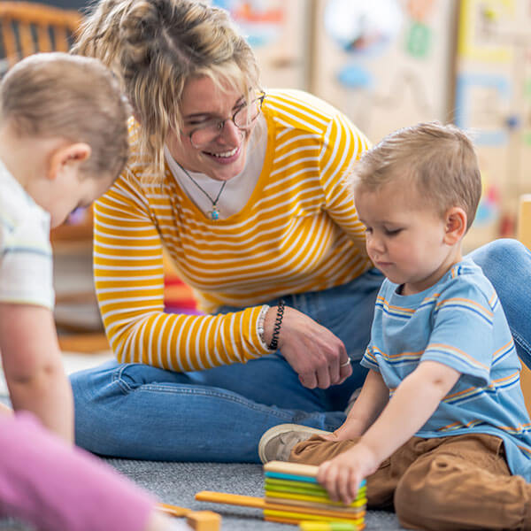 teacher helping young boy play with blocks