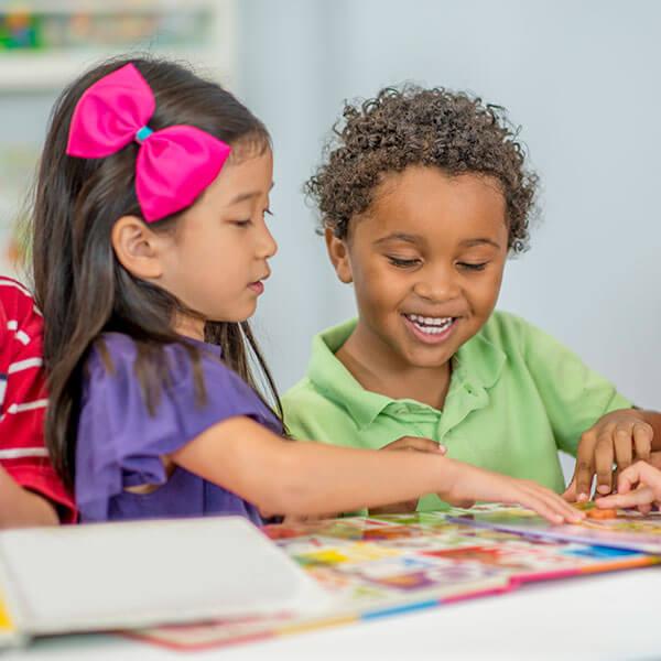 young children playing together with book